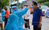 防疫工作人員給峴港市五行郡市民測量體溫。(圖源:越通社)