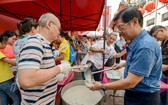 1月13日，在馬來西亞吉隆坡的茨廠街，當地華人社團分發臘八粥給市民。（圖源：新華社）