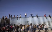 攀爬美墨邊境隔離牆的移民者試圖入境美國。（圖源：互聯網）