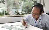 張漢明在瓷板上繪畫。 