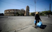 當地時間4月10日，一名婦女背著垃圾袋穿過羅馬體育館紀念碑附近。（圖源：互聯網）
