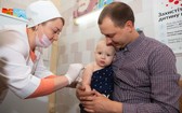 一名嬰兒被父親抱在懷中，接受護士接種的第一劑麻疹、腮腺炎和風疹三聯疫苗。（圖源：Unicef）