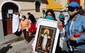 玻利維亞首都拉巴斯的「大能耶穌天主堂」外，信徒們戴口罩，拿著耶穌畫像遊行。（圖源：AP）