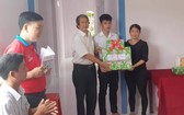 阮文菜老師在向阮陳日輝家庭贈送禮物分享入住新屋的喜悅。