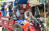 四隱先生駕著載滿衣服的電動三輪車走遍各條大街小巷去派發。