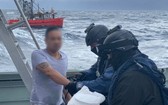 全副武裝的執法人員在浪高3.5米的惡劣環境下在海上突襲小船，逮捕了3人。（圖源：Getty Images）