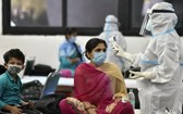 印度衛生部：印度新冠累計死亡病例於3日突破10萬例。圖為防疫人員在給一名婦女測量體溫。（圖源：互聯網）