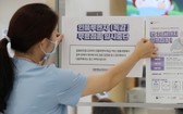 韓國世宗一間醫院的職員正在醫院入口處張貼告示，提醒民眾流感疫苗接種計劃暫停。 （圖源：路透社）