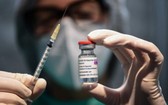 圖為醫務人員拿著一個注射器和一小瓶 AstraZeneca 新冠病毒疫苗。（圖源：AFP）
