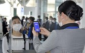 日本首次試行在機場辦理登機手續時，採用新冠病毒防疫電子通行證。（圖源：共同社）