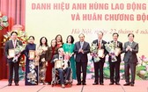 國家主席阮春福（右四）與榮獲革新時期勞動英雄稱號的代表及家屬合照。（圖源：越通社）