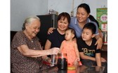黃振英-謝珍（左一、二）母女一家四代人高興地圍著一瓶陳年鹹金桔。
