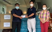 華人熱心人士鄧栢榮、區美莉伉儷(右)向第十一郡第一坊領導移交支持防疫物資。