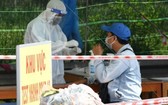 茶榮省防疫工作人員在一個檢疫點為一名過站男性進行快捷核酸檢測。（圖源：胡江）