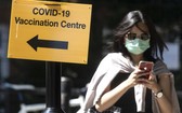 7月16日，行人走過英國倫敦街頭一個疫苗接種點的標誌牌。（圖源：新華社）