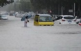 中國河南鄭州強降雨，行人20日涉水通過積水路段。（圖源：互聯網）