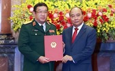 國家主席阮春福（右）向國防部副部長范懷南中將頒授晉升上將軍銜《決定》。（圖源：越通社）