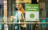 在加拿大多倫多一座車站，一名戴口罩的女子從提醒人們戴口罩的告示旁走過。
