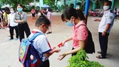 A teacher gives hand wash to her student (Photo: SGGP)