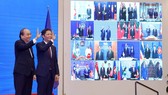 Vietnamese Prime Minister Nguyen Xuan Phuc (left) and Minister of Industry and Trade Tran Tuan Anh, together with leaders of other RCEP member countries, witness the pact signing via videoconference on November 15 (Photo: VNA)