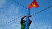 Ngư dân kiểm tra lại dây buộc Quốc kỳ trước khi cho tàu ra khơi. Ảnh: NLĐ