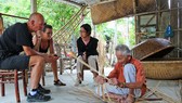 Ông Vũ Văn Khá (làng Kim Bồng, xã Cẩm Kim, TP Hội An) biểu diễn nghề đan thúng chai cho khách nước ngoài thưởng lãm