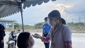 Kiểm tra thân nhiệt cho người đi đường tại chốt kiểm soát dịch trên Quốc lộ 1K phường Hóa An, TP Biên Hòa