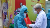 Bí thư Quận ủy quận 7 Võ Khắc Thái trao quyết định kết nạp Đảng cho đảng viên mới tại điểm cách ly ở Trường Mầm non Phú Thuận. Ảnh: GIA BẢO