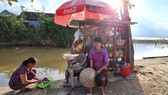 Chị Lê Thị Trang bên quán tạp hóa nhỏ ven bờ kênh. Ảnh: MINH PHONG