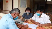 Chi trả tiền hỗ trợ cho người dân gặp khó khăn do Covid-19. Ảnh: TTXVN