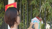 Cô giáo Nguyễn Thị Bích Trâm, trường Tiểu học Tây Hồ bỏ pin vào ngôi nhà được treo trước hàng rào của trường