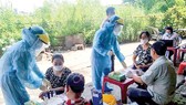 Nhân viên Trung tâm Y tế huyện Bình Chánh lấy mẫu xét nghiệm người dân tại tại chợ Tân Đoàn Việt - Phong Phú vào sáng 2-5. Ảnh: MINH NAM
