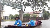 Người dân huyện Quảng Điền, tỉnh Thừa Thiên - Huế di chuyển trên đường ngập lụt, chiều 17-10. Ảnh: VĂN THẮNG
