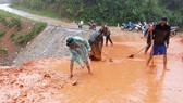 Bộ đội Biên phòng tỉnh Quảng Trị cùng người dân dọn bùn đất trên tuyến đường liên xã ở huyện Đakrông (Quảng Trị). Ảnh: NGUYỄN HOÀNG