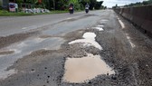 Mặt đường quốc lộ 1A, hư hỏng, lổm chổm đá dăm.