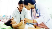 Dr. Tran Thi Kim Van is examining a kid with hand-foot-mouth disease (Photo: SGGP)