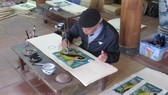 Artisan Nguyen Dang Che finishes a Dong Ho painting called Ca Chep Trong Trang (Moonlight Carp) (Photo: VNA)