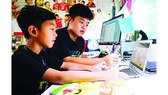Third-grader Nguyen Huynh Thong is getting used to e-learning with the help of his brother, a seventh grader. (Photo: SGGP)