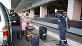 Medical workers spray with Chloramin B disinfectant for passenger's luggage