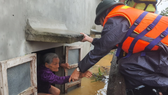 A rescue worker take an old woman out from her flooded house in Quang Binh Province (Photo: SGGP)