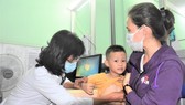 Bác sĩ Trạm y tế phường 2, quận Tân Bình đang khám cho bệnh nhi. Ảnh: QUANG HUY