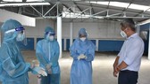 Thứ trưởng Bộ Y tế Nguyễn Trường Sơn thăm hỏi động viên nhân viên y tế lấy mẫu xét nghiệm cho người dân tại phường 25, quận Bình Thạnh.  Ảnh: KHÔI NGUYÊN
