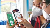 Chị Trần Thị Thanh Trang, huyện Bình Chánh, TPHCM hướng dẫn thành viên gia đình sử dụng app sổ sức khỏe điện tử trên nền điện thoại thông minh. Ảnh: HOÀNG HÙNG
