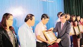 Chairman of the HCMC People’s Committee Nguyen Thanh Phong gives certificates of merit to individuals and organizations well performing tax obligations on August 3 (Photo: SGGP)