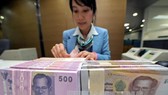 Kiểm tiền baht của Thái Lan tại ngân hàng Krung Thai ở Bangkok. Ảnh: AFP/TTXVN