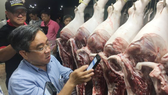 Lãnh đạo Sở Công thương TPHCM kiểm tra quét mã vạch truy xuất nguồn gốc thịt heo tại chợ đầu mối sáng 31-7-2017. Ảnh: THANH HẢI 