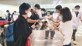 Khách từ Hàn Quốc thực hiện tờ khai y tế tại sân bay Tân Sơn Nhất rạng sáng 24-2. Ảnh: THÀNH SƠN