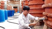 Kiểm tra chất lượng nước mắm trong quá trình rút kéo nước mắm bên trong nhà thùng tại Phú Quốc. Ảnh: NGỌC CHÁNH