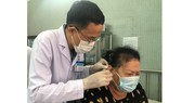 ThS-BS Nguyễn Văn Đàn thực hiện phương pháp nhĩ châm  cho bệnh nhân bị nhức mỏi. Ảnh: MINH NAM