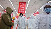 Nhân viên mặc quần áo bảo hộ và khẩu trang phòng chống dịch bệnh viêm phổi lạ do nhiễm virus corona phục vụ khách hàng tại một nhà thuốc ở Vũ Hán, Trung Quốc, ngày 25/1. Ảnh: AFP/TTXVN